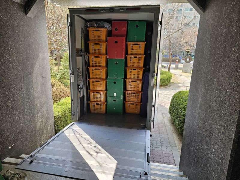 건물 입구 기둥 사이로 보이는, 칸칸이 짐을 실은 탑차 짐칸