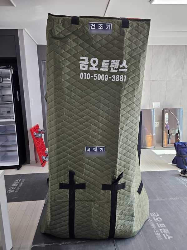 세탁기와 건조기에 상호가 인쇄된 누빔 커버를 씌운 모습